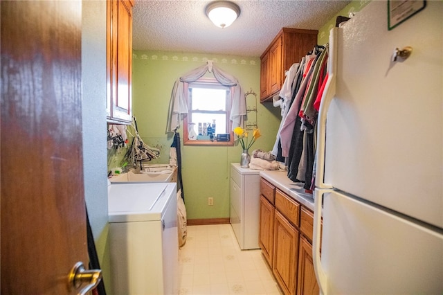 clothes washing area with cabinets, washer and dryer, and a textured ceiling