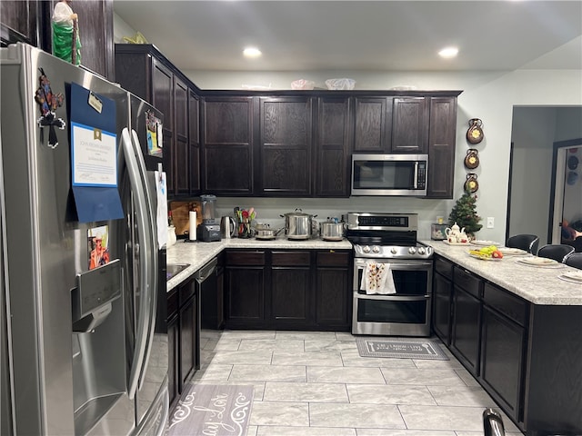 kitchen featuring kitchen peninsula, dark brown cabinetry, and appliances with stainless steel finishes