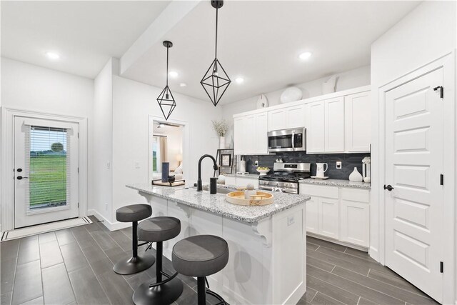 6309 NW Harley St, Bentonville, AR 72713 - kitchen featuring stainless steel appliances, backsplash, an island with sink, white cabinetry, and recessed lighting