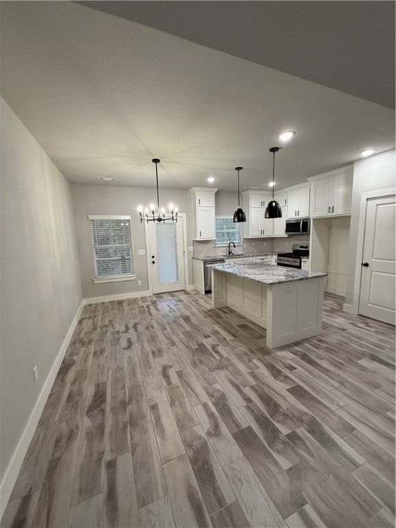 kitchen with white cabinets, a kitchen island, appliances with stainless steel finishes, and light hardwood / wood-style flooring