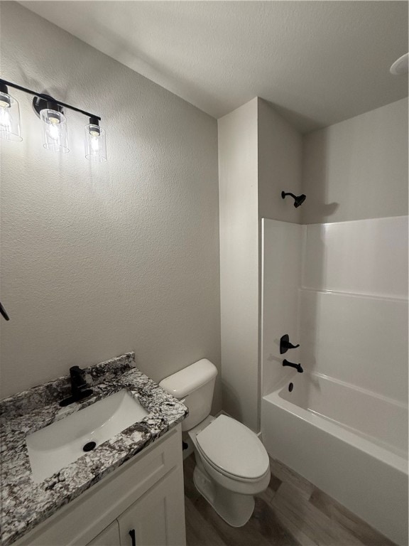 full bathroom featuring vanity, bathing tub / shower combination, toilet, a textured ceiling, and wood-type flooring