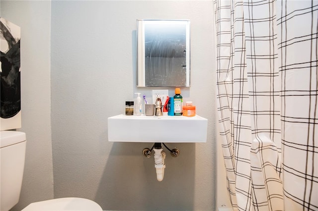 bathroom with walk in shower, sink, and toilet