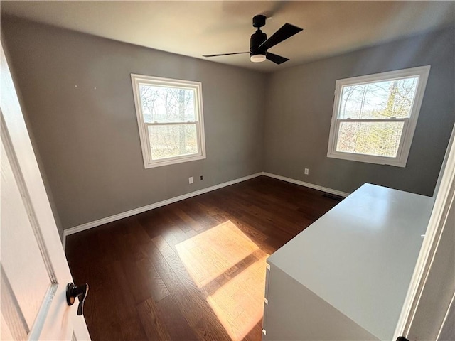 unfurnished room with plenty of natural light, dark wood-type flooring, and ceiling fan