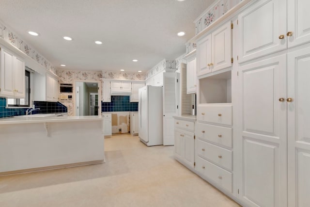 kitchen with white cabinets, white fridge, and a textured ceiling