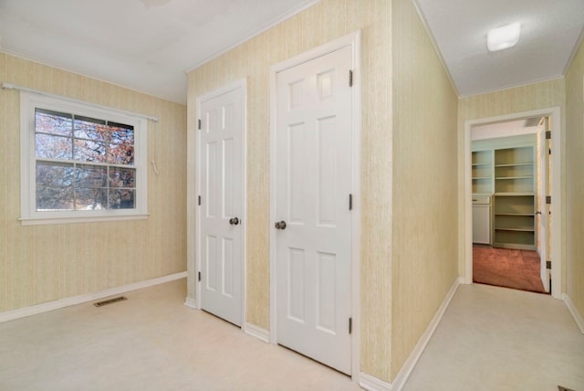 corridor with a textured ceiling, light colored carpet, and crown molding