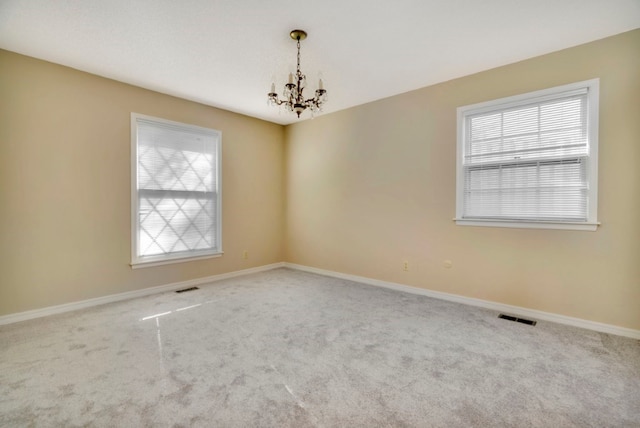 carpeted empty room featuring a chandelier and a healthy amount of sunlight