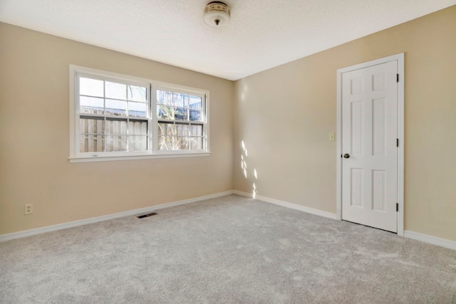 spare room with light carpet and a textured ceiling