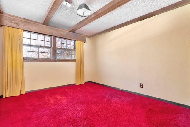 empty room featuring carpet floors, beamed ceiling, and a textured ceiling