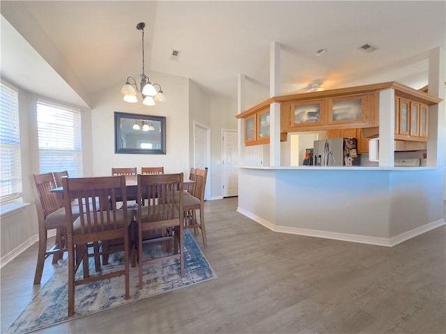 dining area with vaulted ceiling, a chandelier, and dark hardwood / wood-style flooring