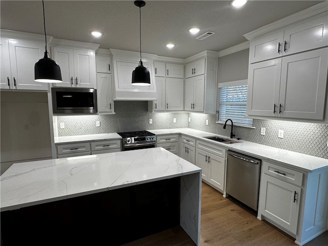 kitchen featuring white cabinets, stainless steel appliances, hanging light fixtures, and sink