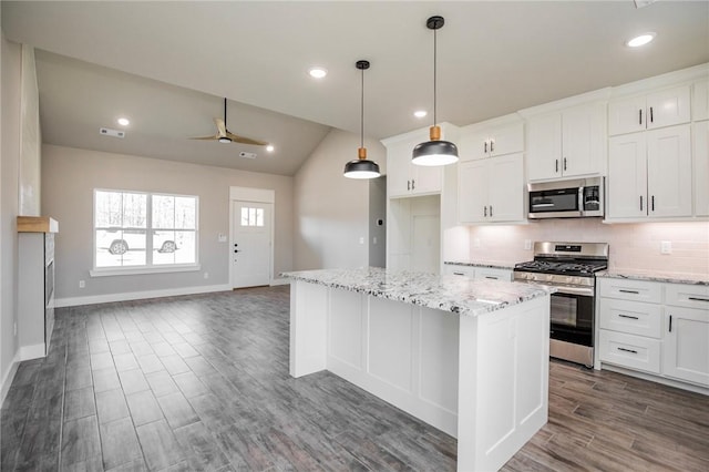 kitchen with appliances with stainless steel finishes, white cabinets, hanging light fixtures, and a center island