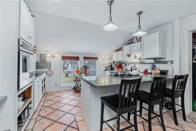 kitchen featuring a kitchen breakfast bar, kitchen peninsula, stainless steel oven, and white cabinets