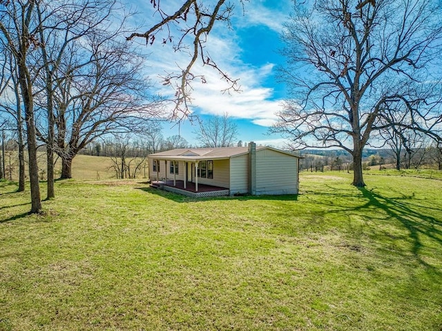 rear view of property featuring a lawn and covered porch