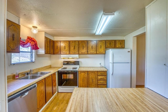 kitchen featuring a textured ceiling, white appliances, light hardwood / wood-style flooring, and sink