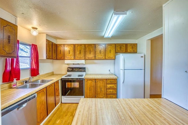 kitchen with a textured ceiling, white appliances, light hardwood / wood-style flooring, and sink