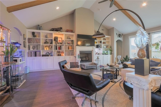 living room with a fireplace with raised hearth, dark wood-style floors, recessed lighting, arched walkways, and high vaulted ceiling