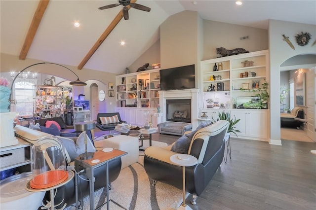 living room with ceiling fan with notable chandelier, a fireplace, wood finished floors, arched walkways, and high vaulted ceiling