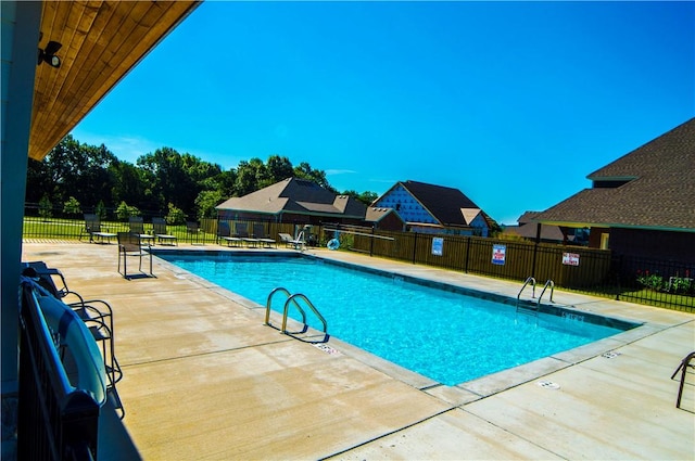 community pool with a patio area and fence