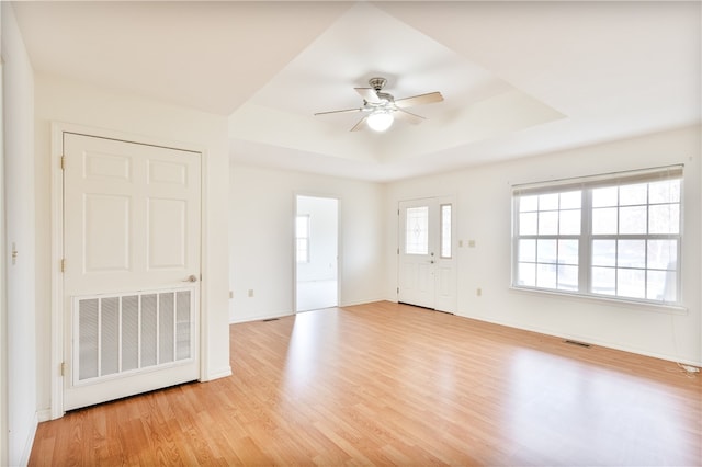 empty room featuring a tray ceiling, light hardwood / wood-style flooring, and ceiling fan