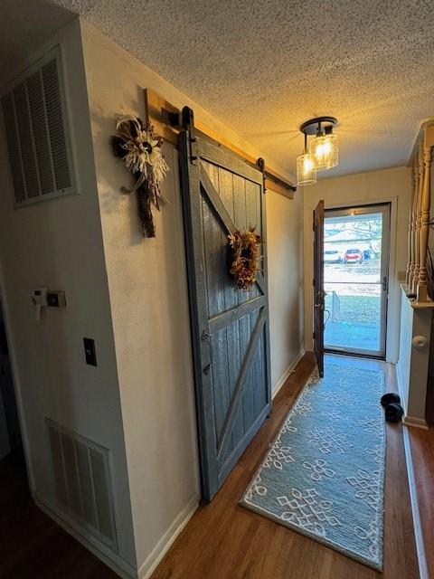 doorway with dark hardwood / wood-style floors, a barn door, and a textured ceiling