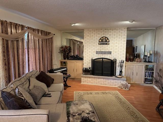 living room featuring a fireplace, a textured ceiling, and light wood-type flooring