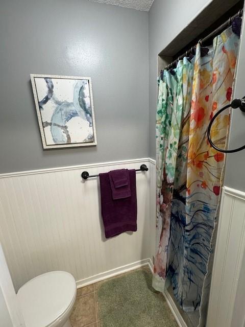 bathroom with tile patterned floors, curtained shower, and toilet