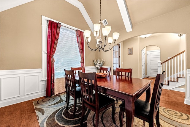 dining space featuring hardwood / wood-style flooring, lofted ceiling with beams, and an inviting chandelier