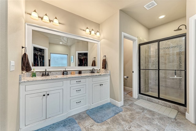 bathroom featuring a shower with door and vanity