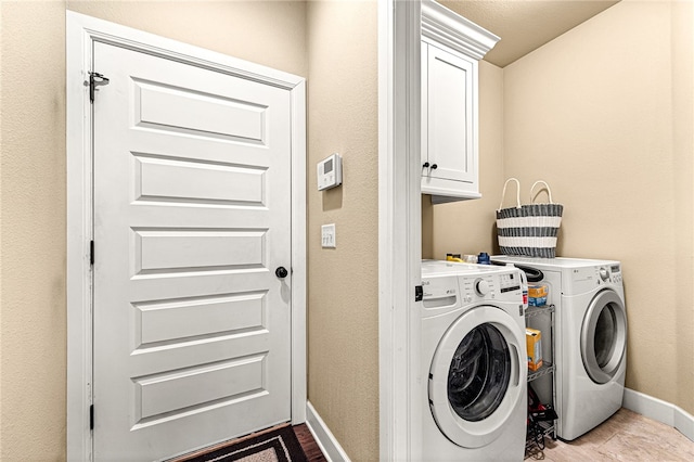 clothes washing area featuring washing machine and dryer, cabinets, and light wood-type flooring