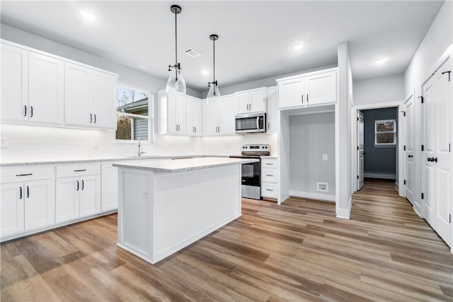 kitchen featuring pendant lighting, stainless steel appliances, a center island, and white cabinets