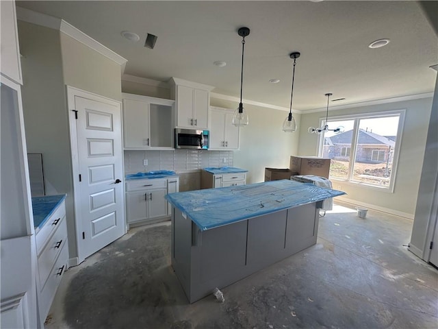 kitchen with backsplash, stainless steel microwave, white cabinets, and crown molding