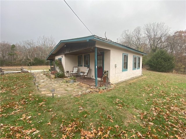 view of side of property featuring a patio area and a lawn