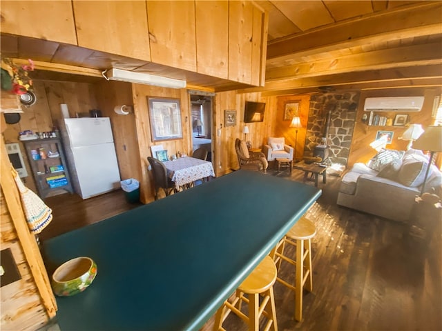 kitchen featuring dark hardwood / wood-style flooring, white fridge, an AC wall unit, and wood walls