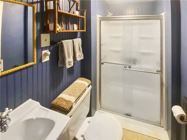 bathroom featuring tile patterned flooring, toilet, a shower with door, and sink