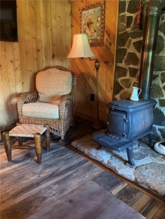 sitting room featuring hardwood / wood-style flooring, a wood stove, and wooden walls