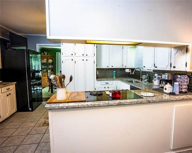 kitchen with white cabinets, black appliances, sink, light tile patterned floors, and ornamental molding