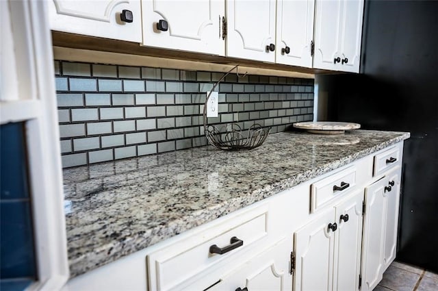 kitchen with white cabinets, light tile patterned floors, tasteful backsplash, and light stone countertops