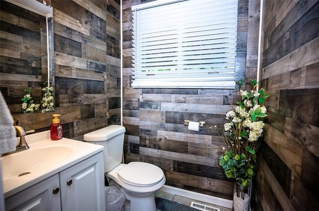 bathroom with wood walls, vanity, and toilet