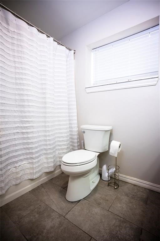 bathroom with tile patterned floors, toilet, and shower / bathtub combination with curtain