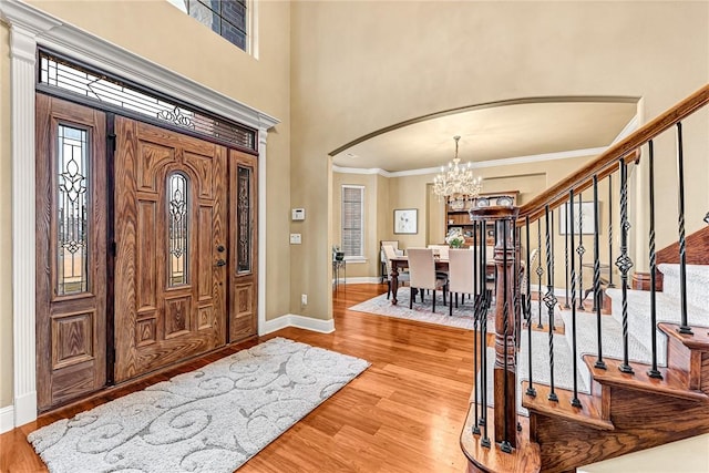 entryway with a notable chandelier, crown molding, and light hardwood / wood-style flooring