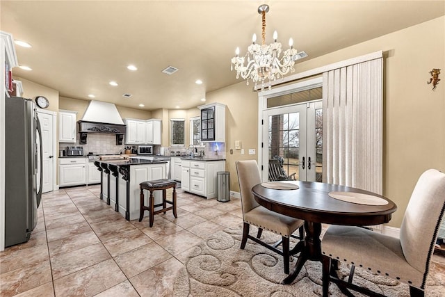 dining room featuring an inviting chandelier, sink, and french doors