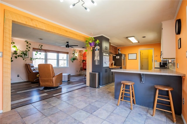 kitchen with sink, a breakfast bar area, fridge, oven, and kitchen peninsula