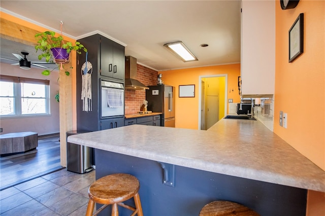 kitchen with a kitchen bar, sink, high quality fridge, kitchen peninsula, and white oven