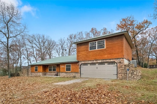 15258 Shipe Rd, Gravette, AR 72736 - view of front of home featuring stone siding, a garage, dirt driveway, and cooling unit