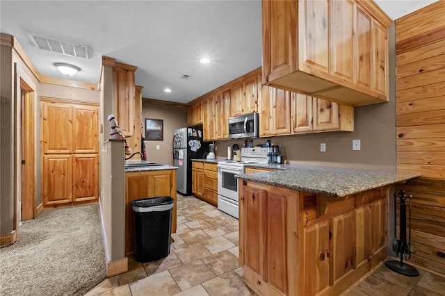 kitchen featuring sink, light brown cabinets, kitchen peninsula, light colored carpet, and appliances with stainless steel finishes