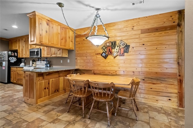 kitchen with kitchen peninsula, appliances with stainless steel finishes, pendant lighting, and light brown cabinetry