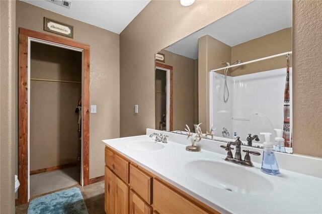 15258 Shipe Rd, Gravette, AR 72736 - bathroom featuring a textured wall, a shower, and double vanity