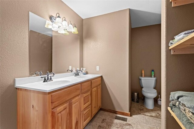 15258 Shipe Rd, Gravette, AR 72736 - bathroom with double vanity, toilet, a textured wall, and tile patterned flooring