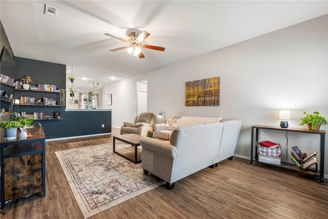 living room featuring dark wood-type flooring and ceiling fan