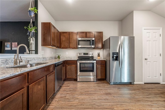 kitchen featuring light stone counters, sink, light wood-type flooring, and appliances with stainless steel finishes